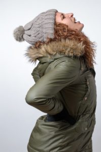 person with back pain wearing a winter coat
