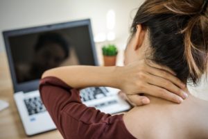 woman with neck pain working at a computer