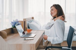 woman sitting at her home office with neck pain