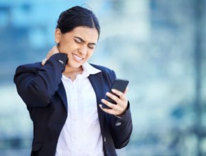 business woman with text neck holding a phone