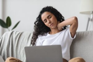 young woman on a laptop with neck pain