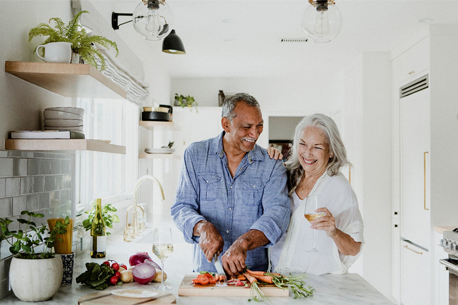 Older couple smiling and making healthy food together.